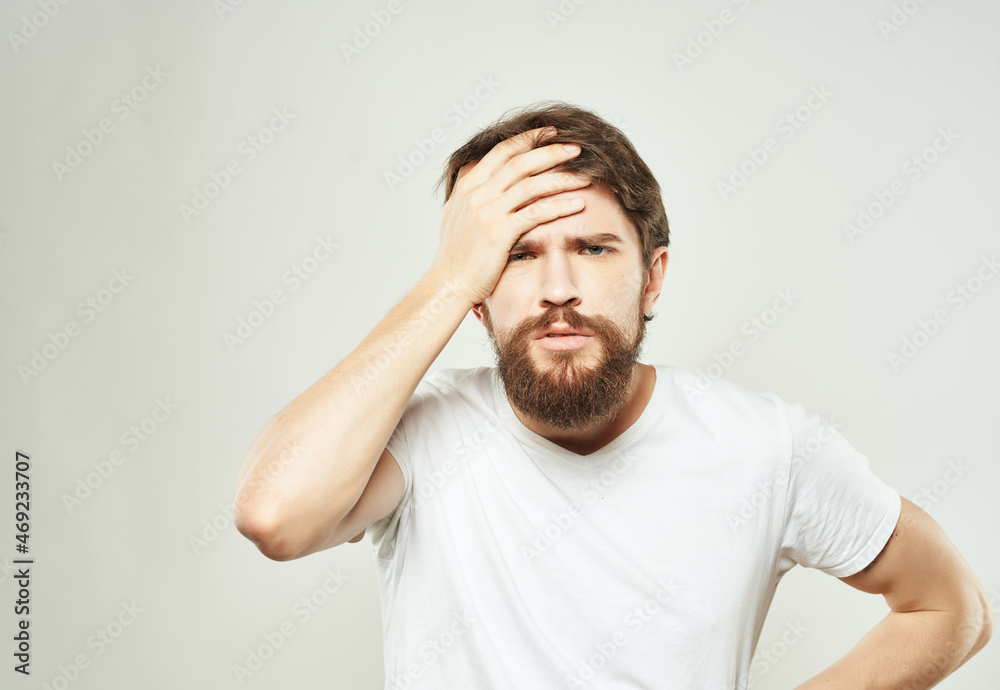 Man in a white t-shirt irritated facial expression light background Man in a white t-shirt irritated facial expression light background