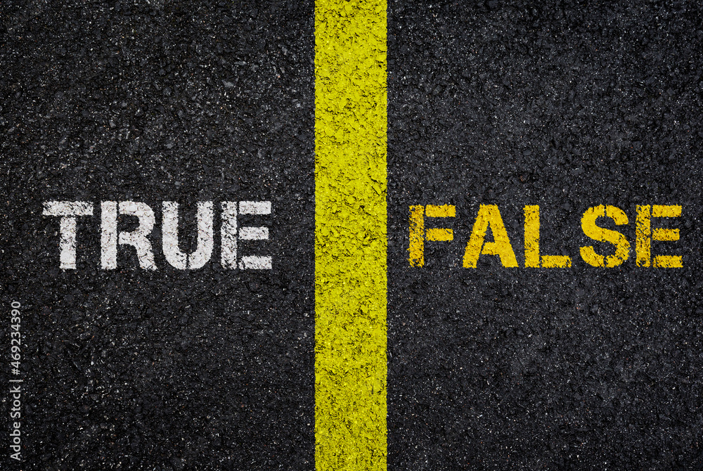 Antonym concept of TRUE versus FALSE, written on dark wet asphalt. Top view. Yellow road marking line between the words. High resolution full frame textured background, viewed from above.