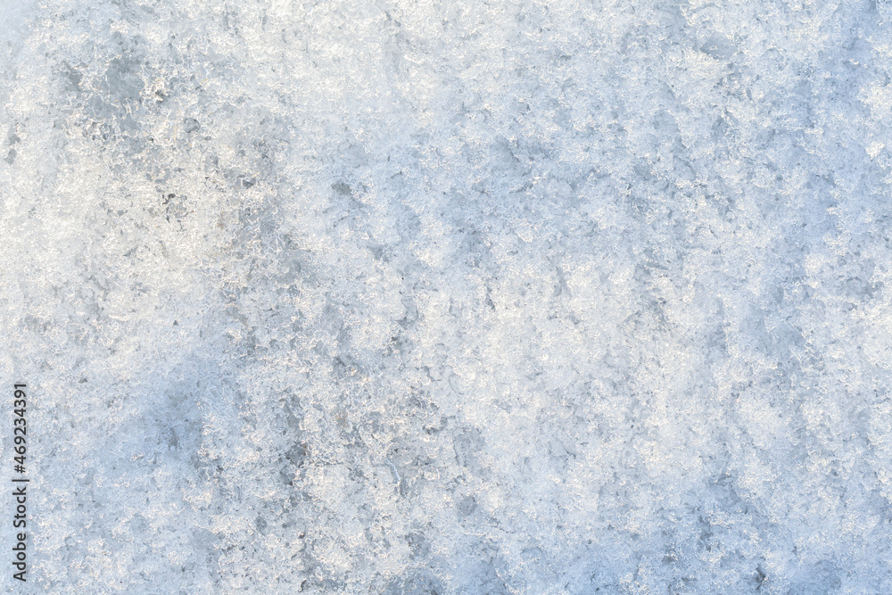 Close-up of fresh shiny snow on the ground on a sunny day, top view. Abstract natural textured background, copy space.