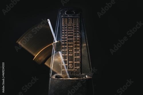 Metronome with moving rod on black background photo