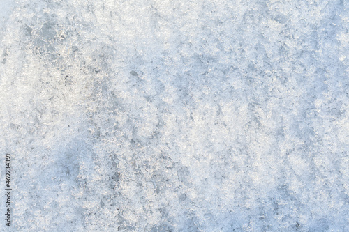 Close-up of fresh shiny snow on the ground on a sunny day, top view. Abstract natural textured background, copy space.