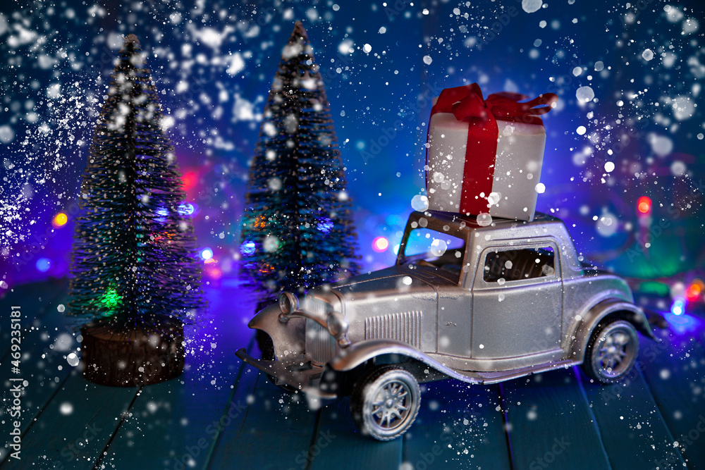 Retro car with a gift on the roof against the background of Christmas lights.