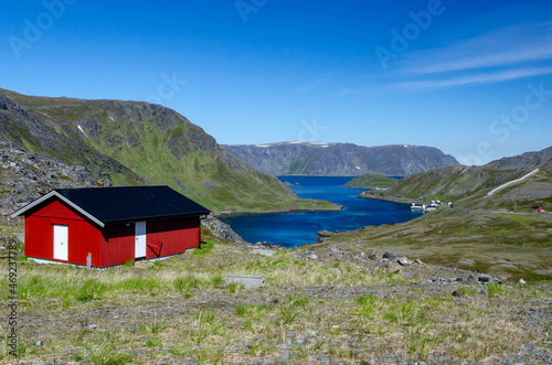Lonely red house on the shores of Norwegian fjord with rocky shores