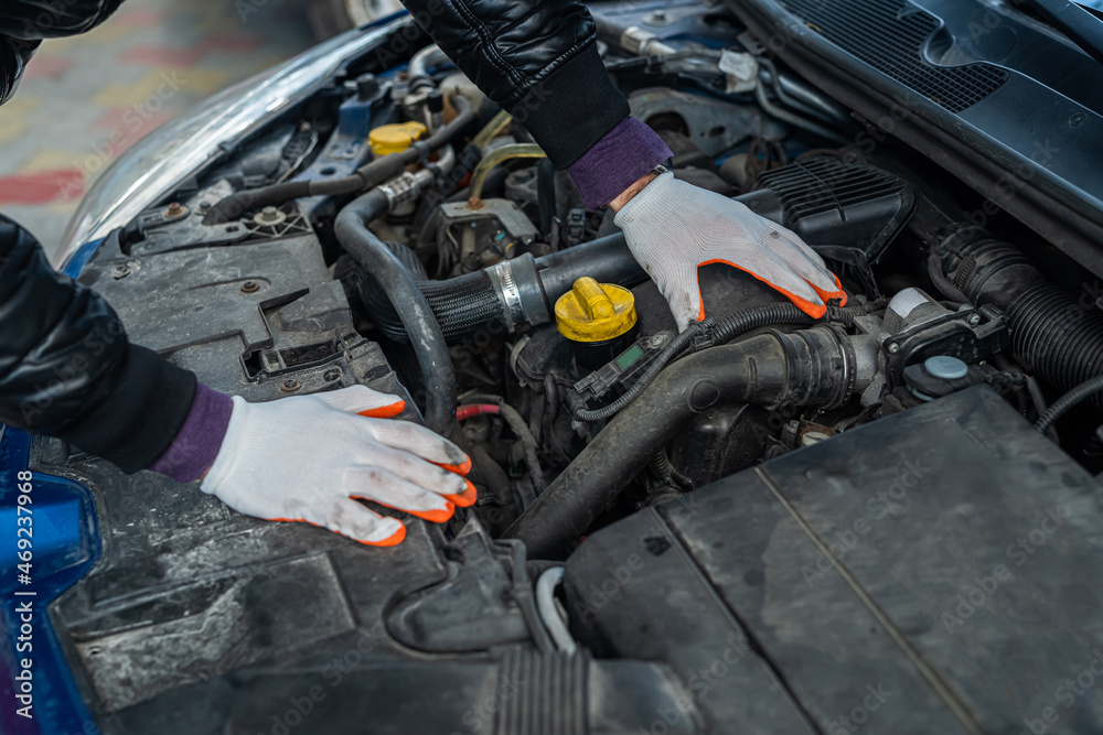 hands of the professional mechanic in special gloves carry out check of the car under a cowl hands of the professional mechanic in special gloves carry out check of the car under a cowl