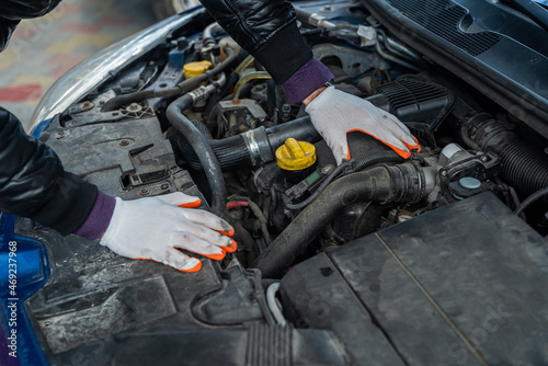 hands of the professional mechanic in special gloves carry out check of the car under a cowl