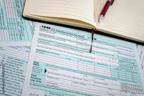 new US tax forms 1040 with a red pen and notebook are spread out on the table