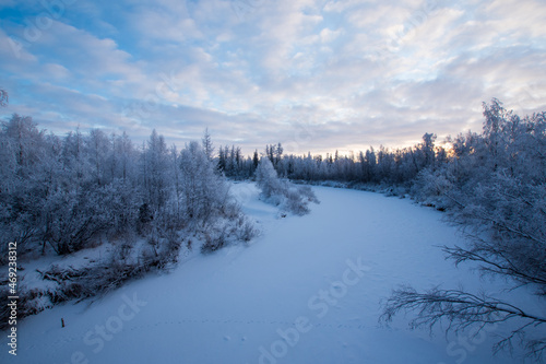 Winter river in the forest, trees are white with frost