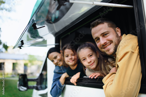 Happy young family with two children looking out of caravan window.