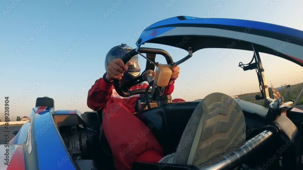 Raceway driver is riding a go-cart through the circuit