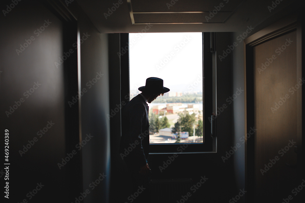 Silhouette of man in hat on background of window Silhouette of man in hat on background of window
