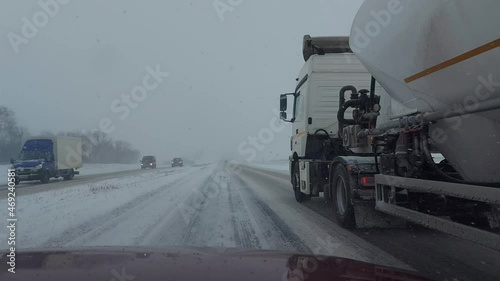 Overtaking a truck with a semi-trailer on a snowy highway in bad weather in winter. Slippery road from ice, colley on the road
