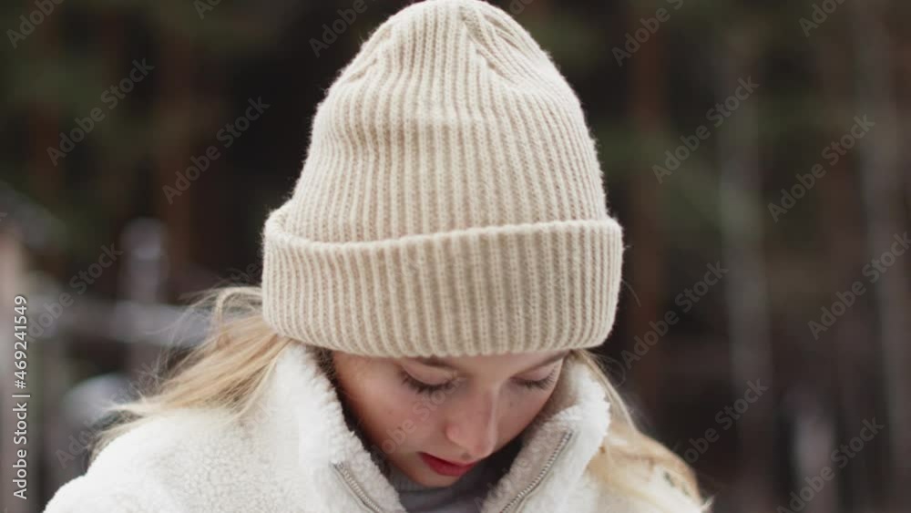 Portrait beautiful teenager white girl zip up fur jacket on winter street. Young woman in knitted hat zipping up winter jacket outdoor. Portrait beautiful teenager white girl zip up fur jacket on winter street. Young woman in knitted hat zipping up winter jacket outdoor.