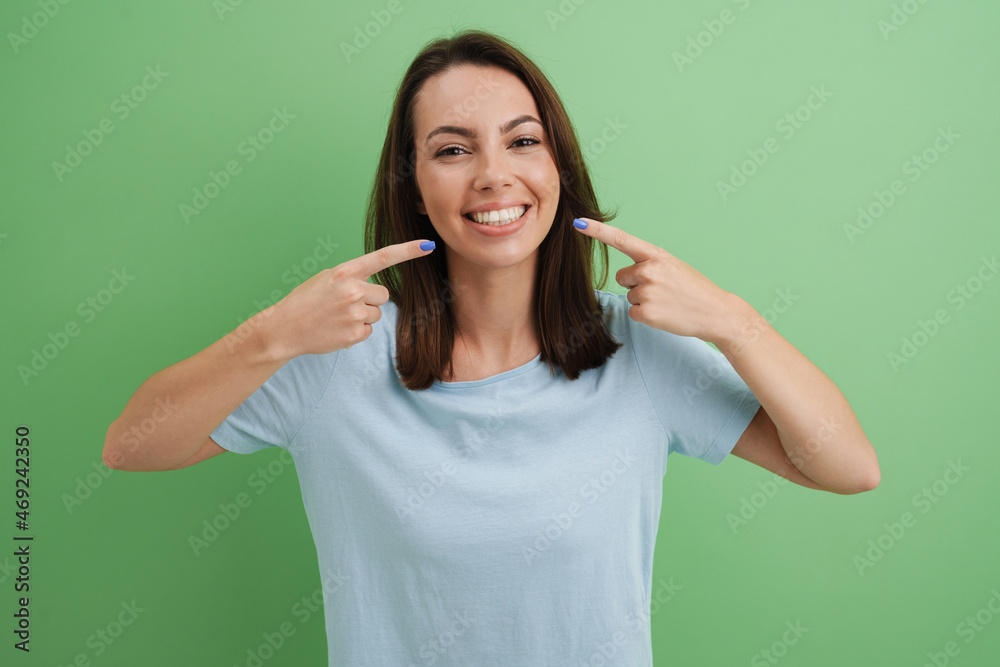 Young european woman in t-shirt pointing fingers at her smile Young european woman in t-shirt pointing fingers at her smile