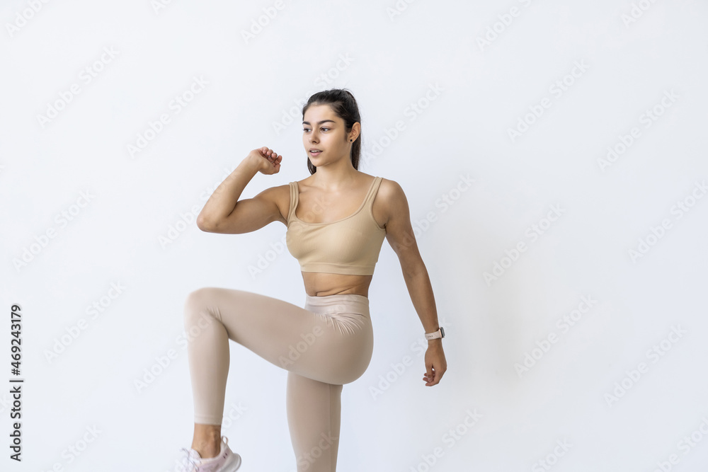 Young beautiful brunette doing step aerobics on white background