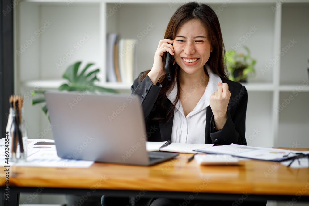 Shot of an Asian young businesswoman working on a laptop computer in her workstation.Portrait of Business people employee freelance online marketing e-commerce telemarketing concept. Shot of an Asian young businesswoman working on a laptop computer in her workstation.Portrait of Business people employee freelance online marketing e-commerce telemarketing concept.