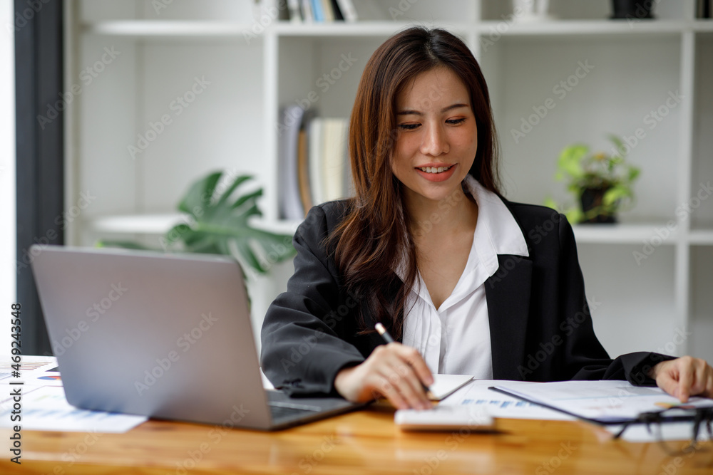 Shot of an Asian young businesswoman working on a laptop computer in her workstation.Portrait of Business people employee freelance online marketing e-commerce telemarketing concept. Shot of an Asian young businesswoman working on a laptop computer in her workstation.Portrait of Business people employee freelance online marketing e-commerce telemarketing concept.
