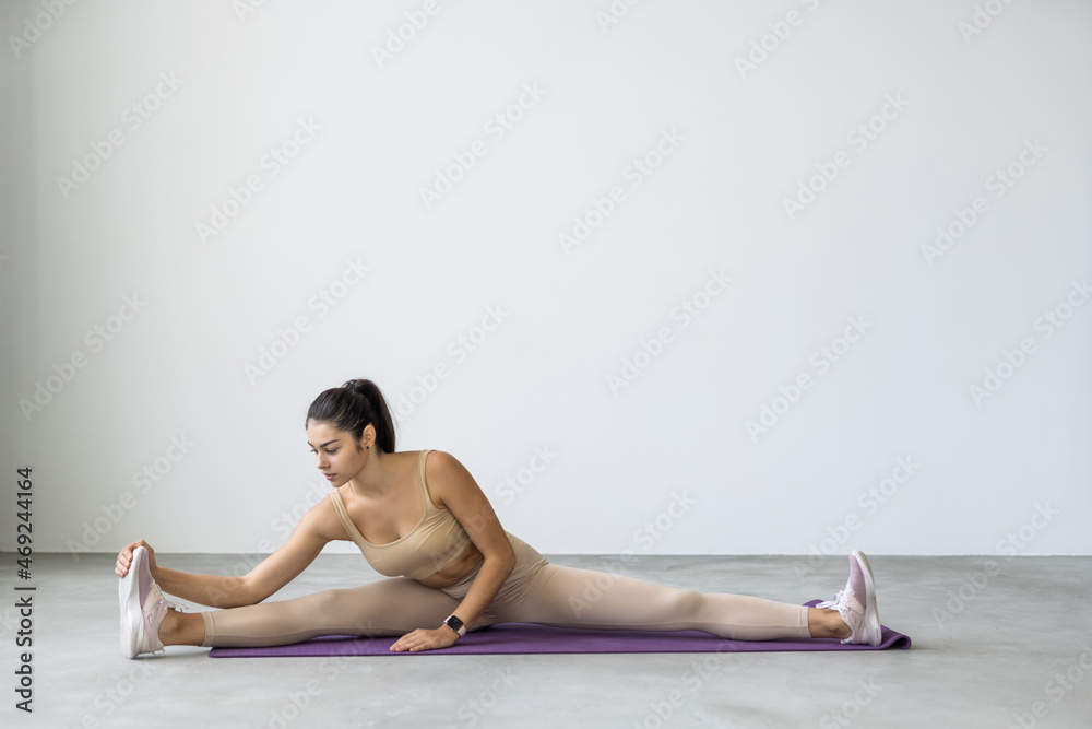 Young woman sitting in gymnastic split at home, indoor stretching training Young woman sitting in gymnastic split at home, indoor stretching training