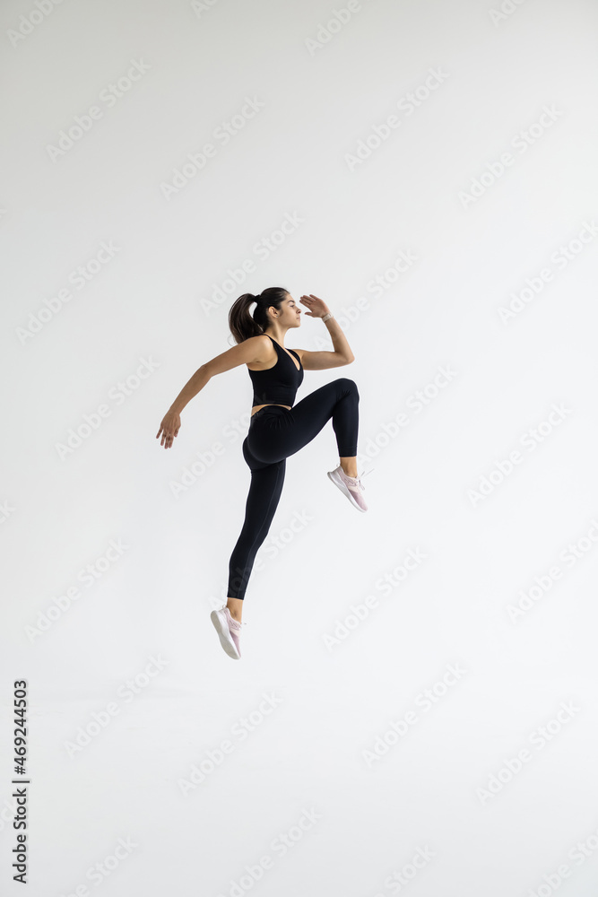 Stylish young woman is engaged in aerobics Jumping exercises. Sports trainer fit chick.