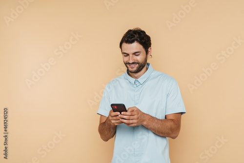 White bristle man wearing shirt smiling and using mobile phone