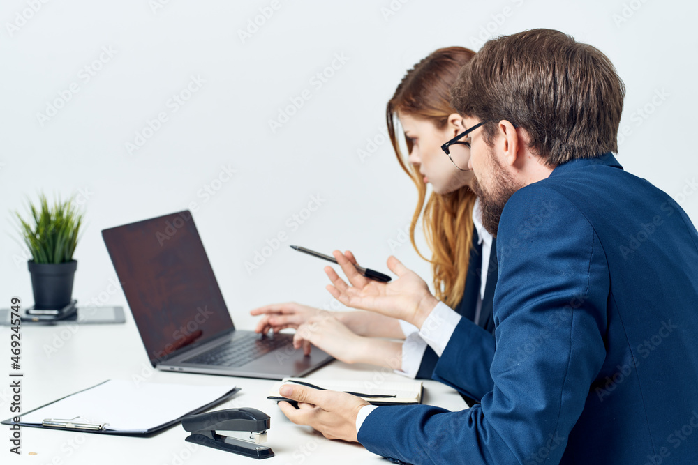 colleagues sitting at a desk in front of a laptop officials colleagues sitting at a desk in front of a laptop officials