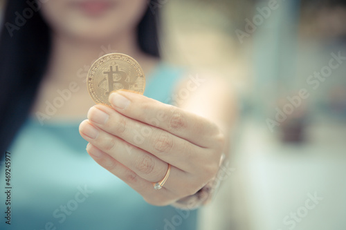 Smiling beautiful Female holding Bitcoin digital currency and cryptocurrency with blur background