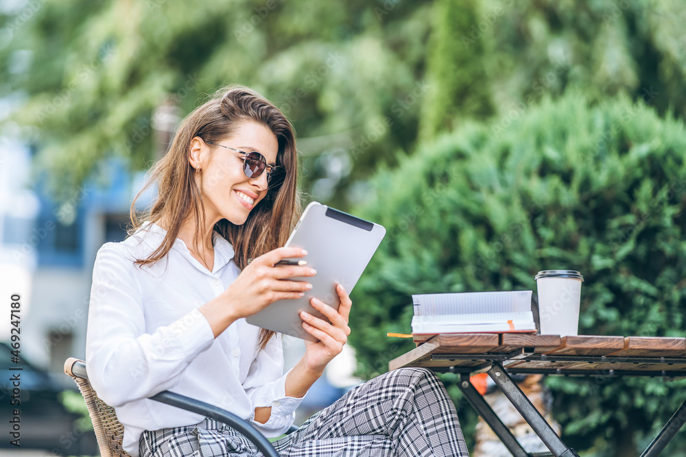 Young business woman drinking coffe and working on tablet in street cafe. Young business woman drinking coffe and working on tablet in street cafe.