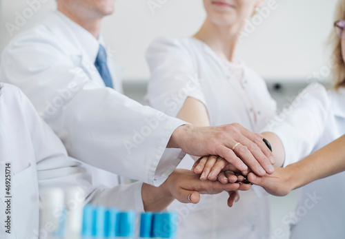 Team of researchers with stacked hands in laboratory