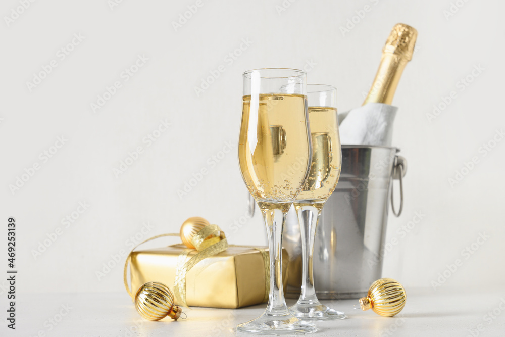 New Year champagne in wineglasses and bottle in bucket decorated festive Christmas gold baubles on white background. Close up. Holiday greeting card with copy space. Happy New Year.