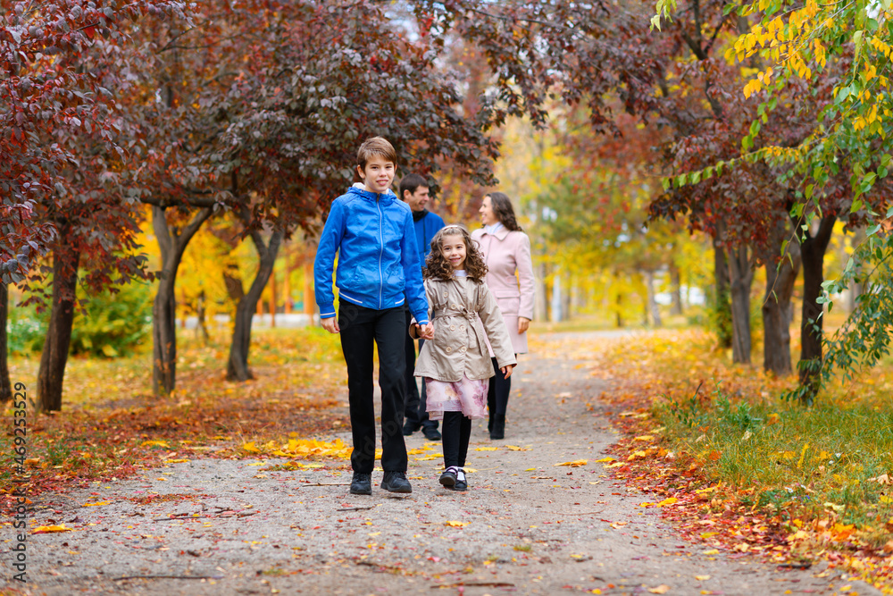 Fototapeta premium children run along the path in the autumn park . they play and laugh, they have a lot of fun. they are surrounded by beautiful nature and trees with yellow and red leaves