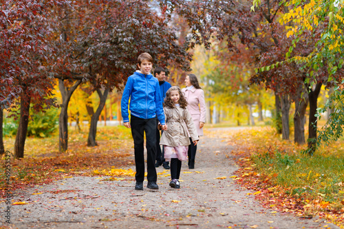 children run along the path in the autumn park . they play and laugh, they have a lot of fun. they are surrounded by beautiful nature and trees with yellow and red leaves