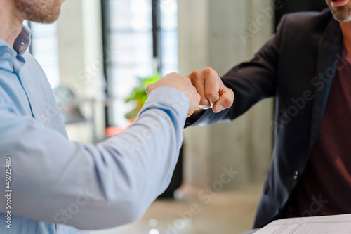 Businessmen giving fist bum to each other in office