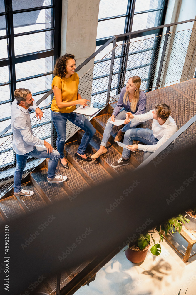 Businesswoman discussing with coworkers on steps in office Businesswoman discussing with coworkers on steps in office