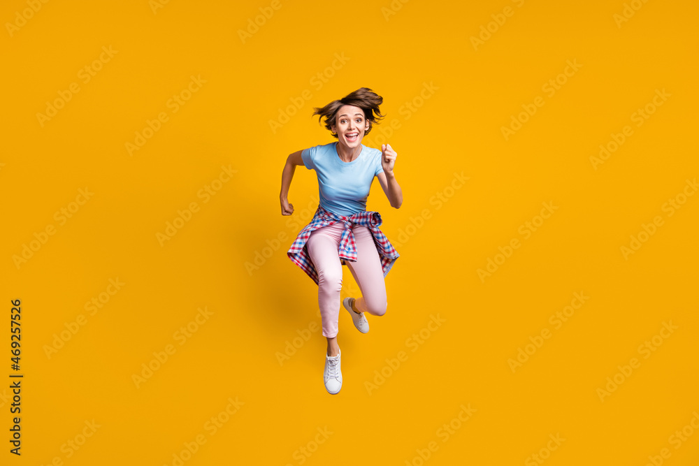 Photo portrait full body view of woman running to camera with tight waist shirt jumping up isolated on vivid yellow colored background