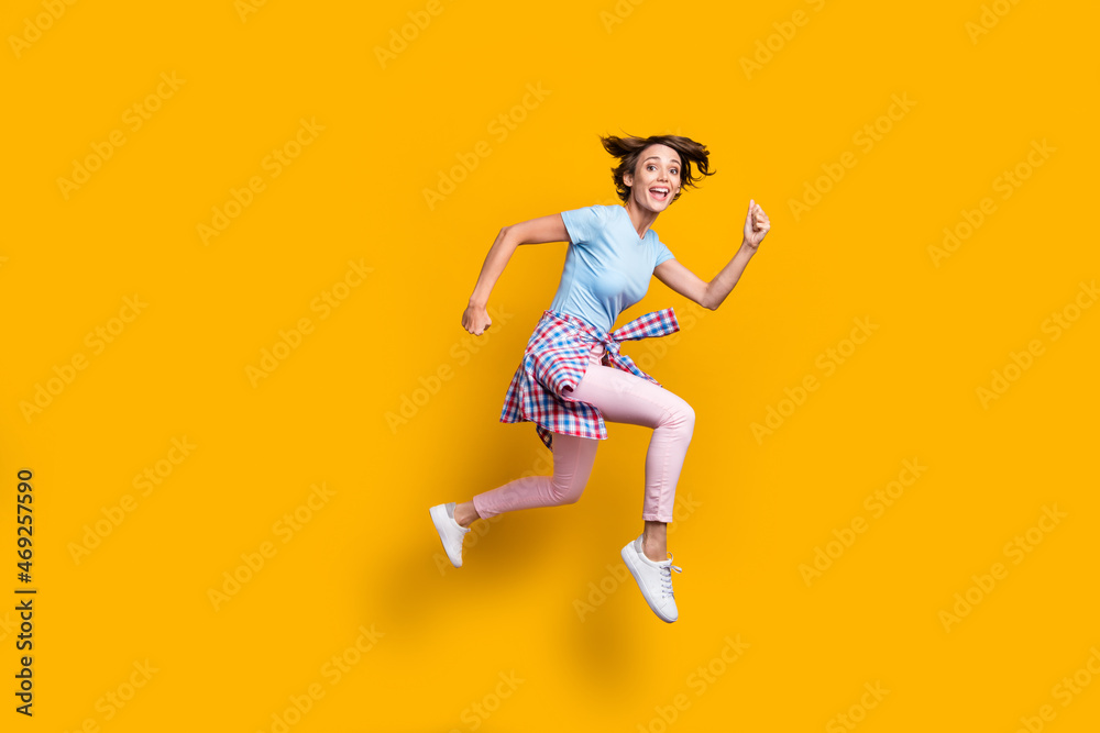 Photo portrait full side body view of crazy girl running with tight waist shirt jumping up isolated on vivid yellow colored background