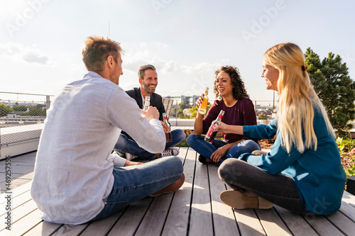 Happy colleagues toasting drinks on rooftop photo