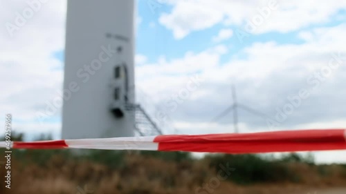 Signal tape marking the boundaries of the restricted area in case of emergencies or repair work on the background of the wind turbine. photo