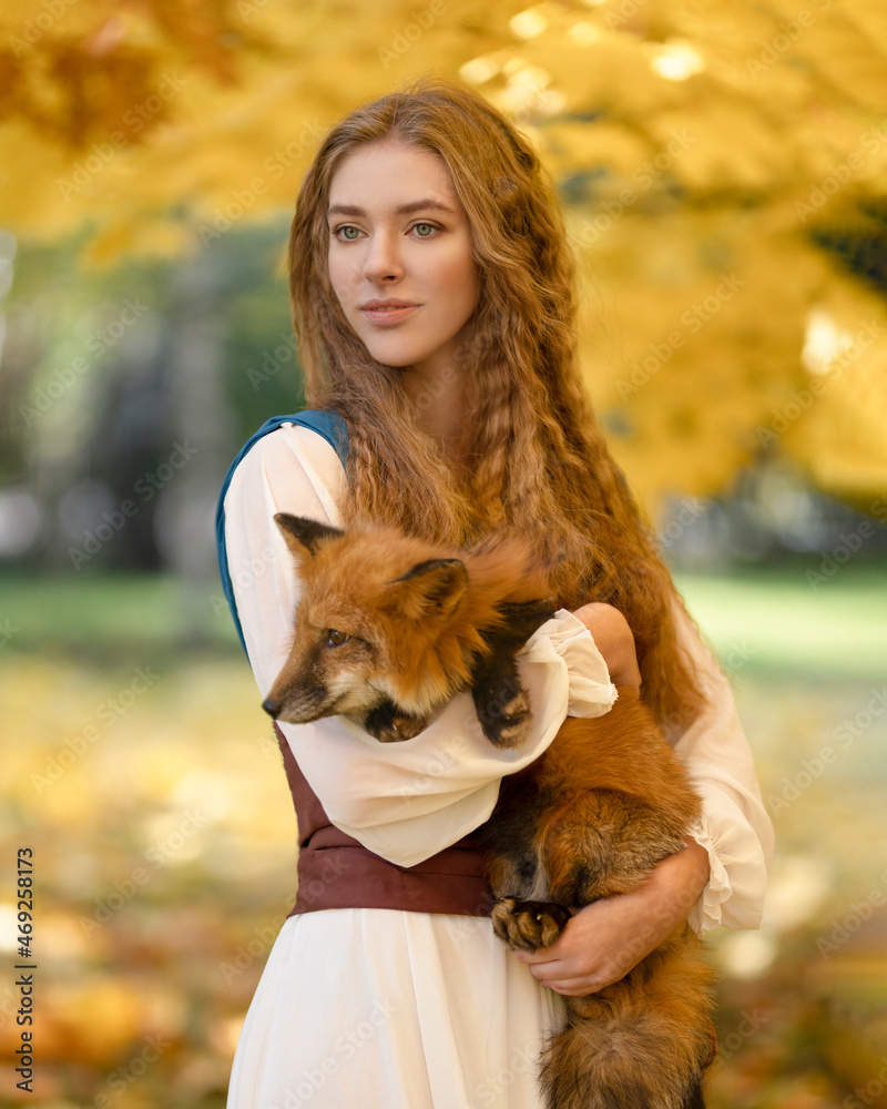 Little red fox in the arms of a girl in the autumn forest Little red fox in the arms of a girl in the autumn forest