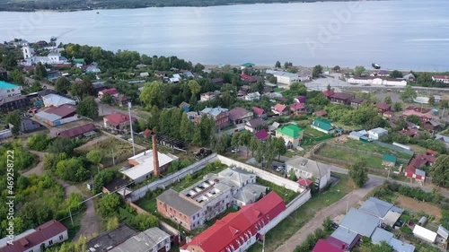 Summer view from drone of small Russian town of Kozmodemyansk in Mari El Republic on banks of Volga river with ancient white Holy Trinity Church between residential buildings. High quality 4k footage photo