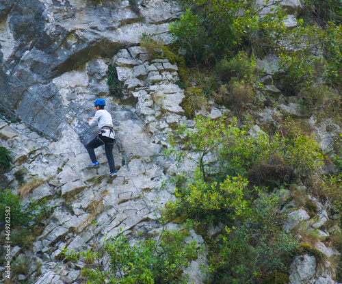 Athletic young man climbing challenging route on a rocky wall.
