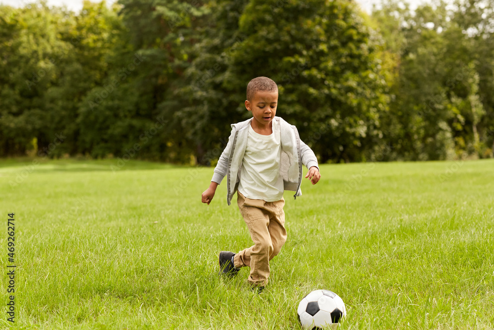 childhood, leisure games and people concept - little boy with ball playing soccer at summer park childhood, leisure games and people concept - little boy with ball playing soccer at summer park