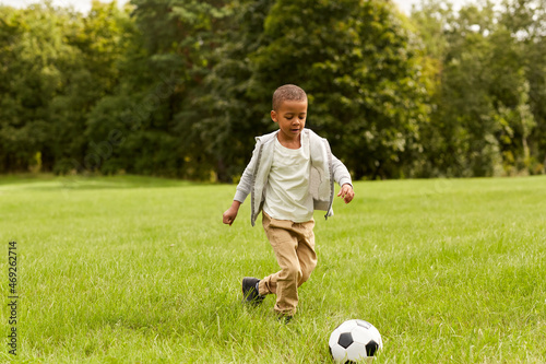 childhood, leisure games and people concept - little boy with ball playing soccer at summer park
