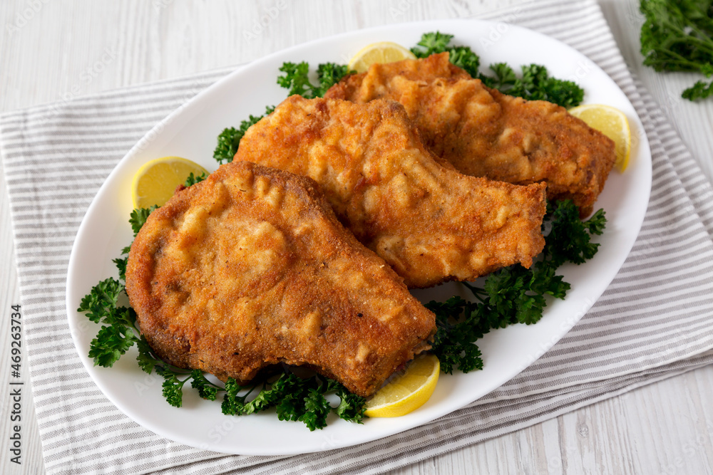 Homemade Fried Pork Chops on a White Plate, low angle view. Homemade Fried Pork Chops on a White Plate, low angle view.