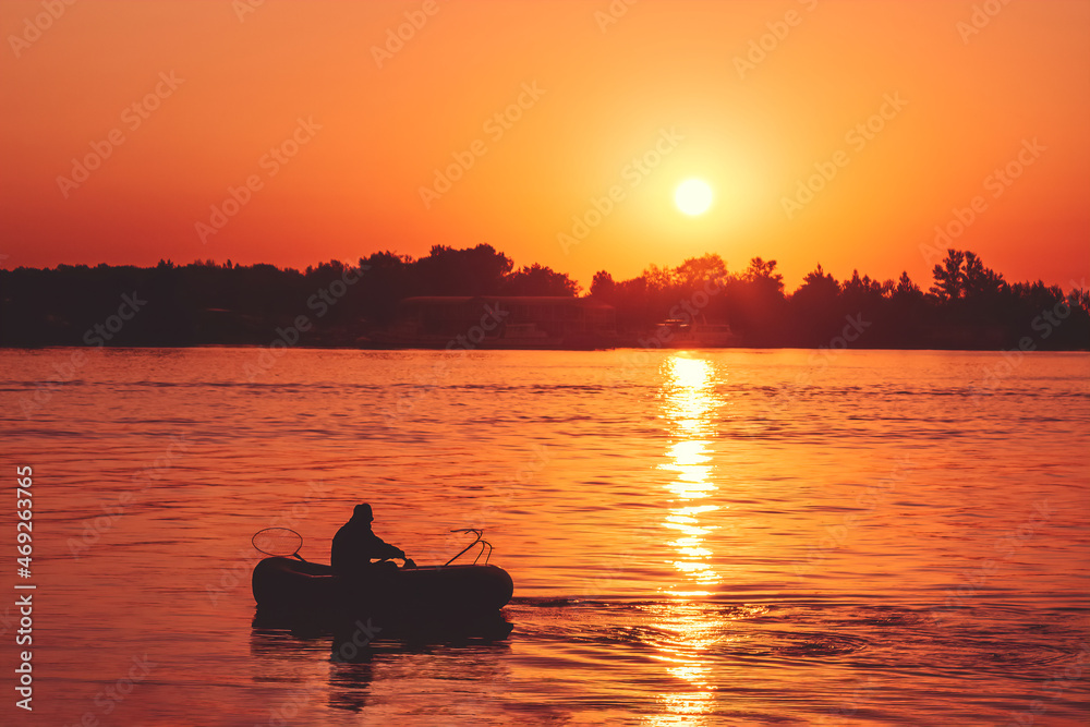 solitary fisher man on rubber boat over Sunrise on beach. Sunset on beach.