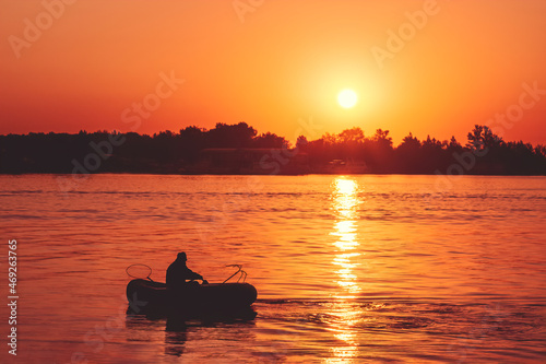 solitary fisher man on rubber boat over Sunrise on beach. Sunset on beach.