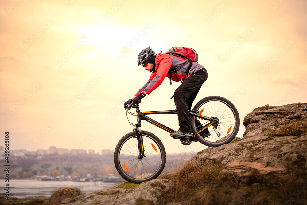 Cyclist Riding the Mountain Bike Down Rocky Hill at Autumn Evening. Extreme Sport and Enduro Cycling Concept. Cyclist Riding the Mountain Bike Down Rocky Hill at Autumn Evening. Extreme Sport and Enduro Cycling Concept.