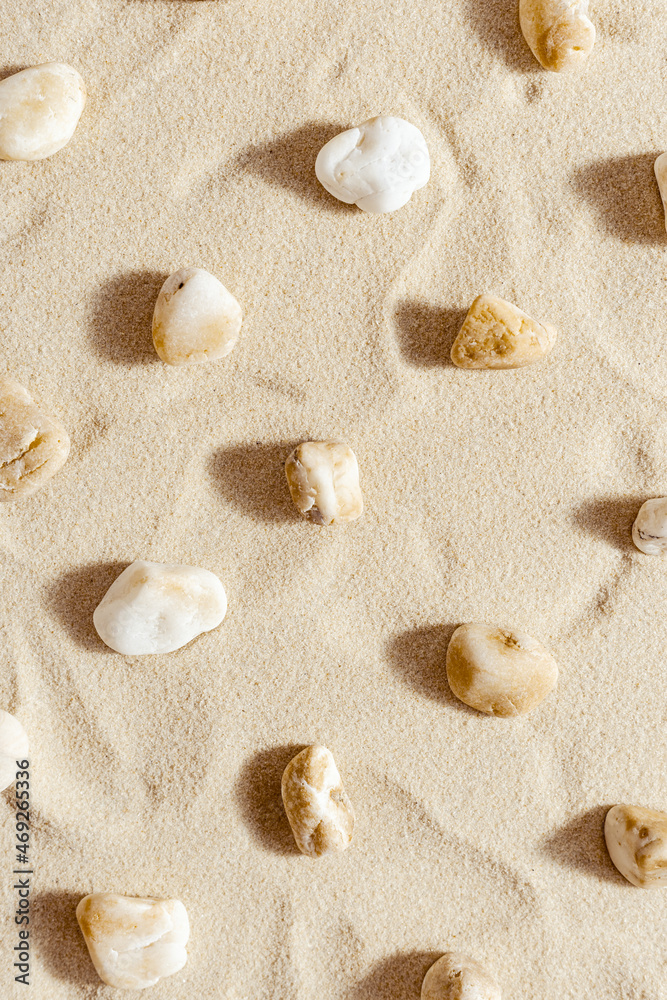 Pattern with pebble sea stones on fine sand. Natural stone neutral beige yellow color, monochrome tones. Summer minimal design background