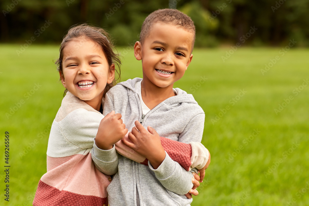 childhood, leisure and people concept - happy smiling little boy and girl hugging at park