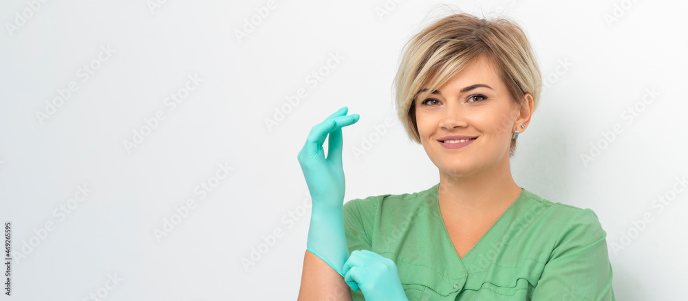 Doctor beautician puts on sterile blue gloves smiling prepares to receive clients on white Doctor beautician puts on sterile blue gloves smiling prepares to receive clients on white