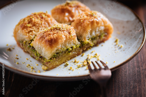 Turkish or Bosnian dessert called Baklava with pistachio served with traditional Turkish or Bosnian coffee set on a wooden board in moody atmosphere