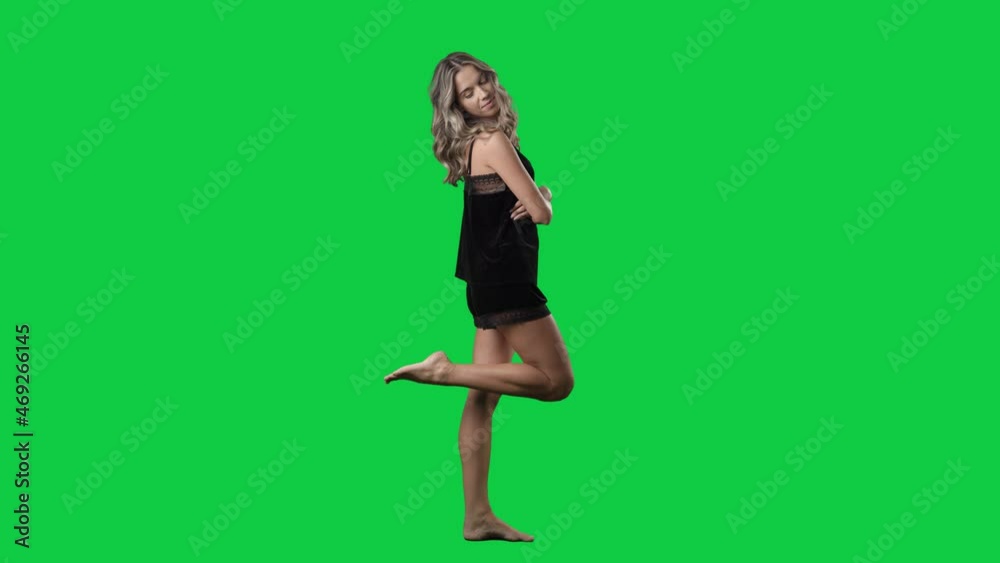 Side view of seductive young woman in black satin sleepwear posing at camera. Full body isolated on green screen background Side view of seductive young woman in black satin sleepwear posing at camera. Full body isolated on green screen background